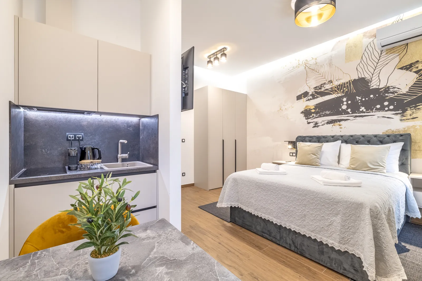 Monolocale per due: letto queen size accanto a un murale botanico